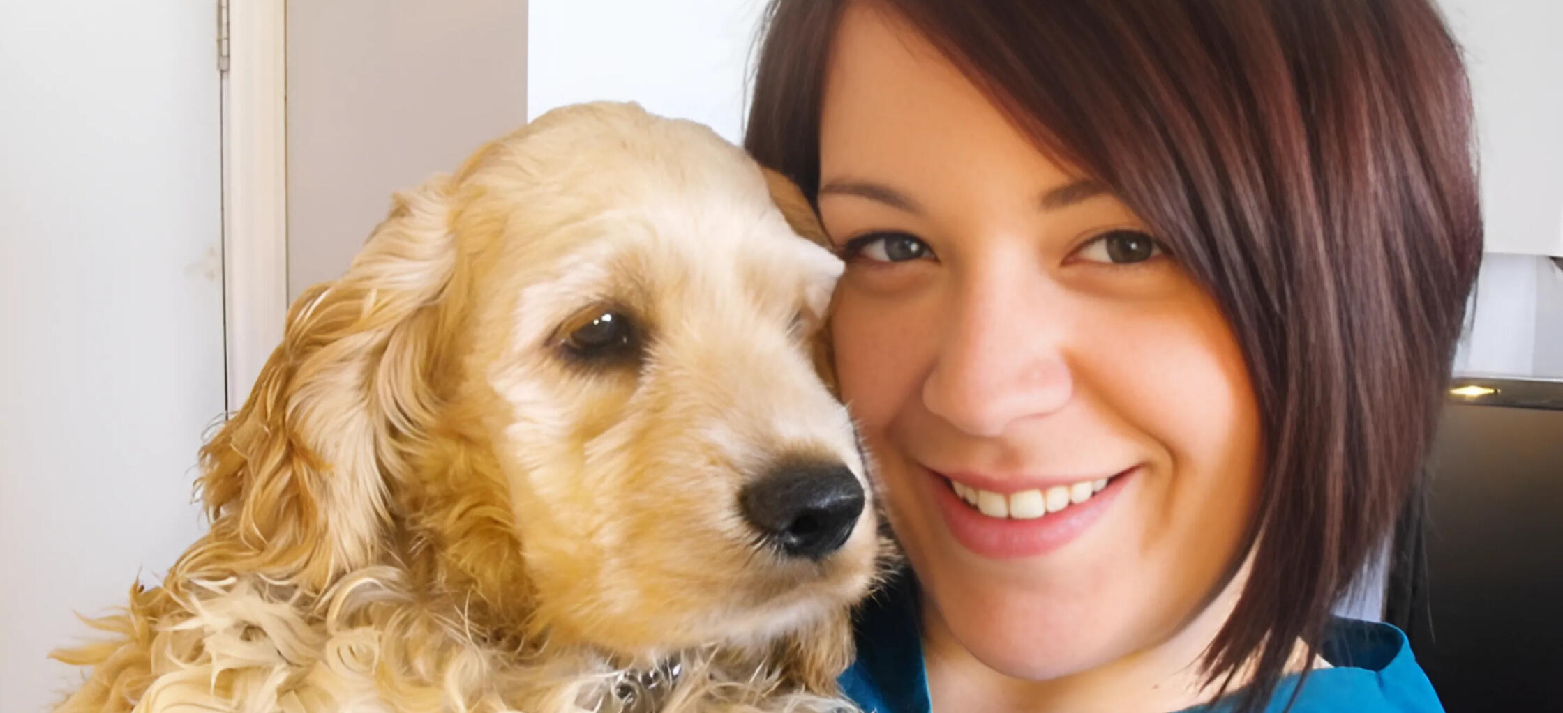 Kirkland Lake Dog Groomer Christina from Critter Cutz smiling while holding a beautifully groomed Cocker Spaniel.